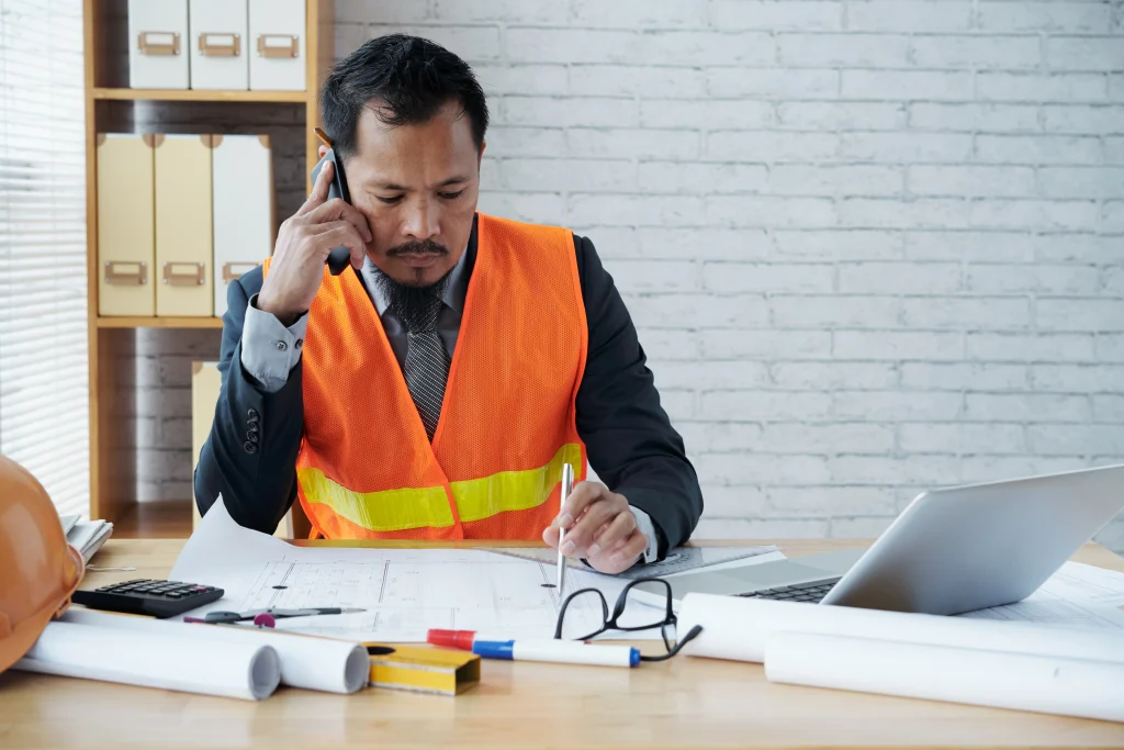 asian-male-construction-firm-executive-sitting-office-talking-phone